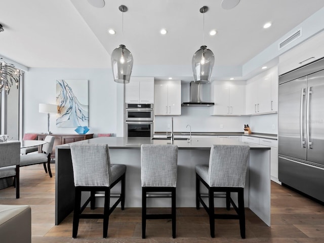 kitchen with white cabinetry, hardwood / wood-style floors, decorative light fixtures, and appliances with stainless steel finishes