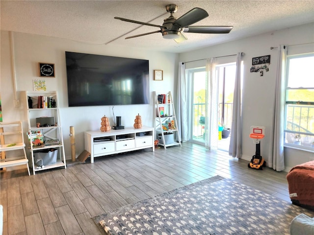 living room with hardwood / wood-style floors, ceiling fan, a healthy amount of sunlight, and a textured ceiling