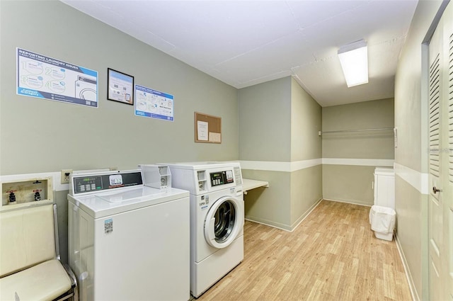 clothes washing area featuring washing machine and clothes dryer and light hardwood / wood-style flooring