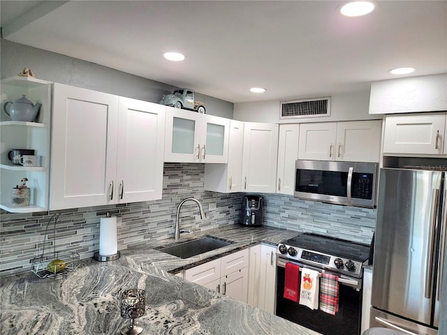 kitchen featuring white cabinets, sink, stainless steel appliances, and dark stone counters