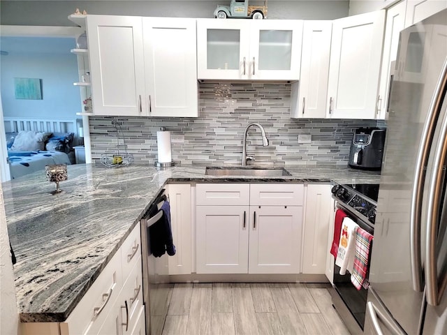 kitchen featuring white cabinets, sink, stainless steel appliances, and dark stone counters