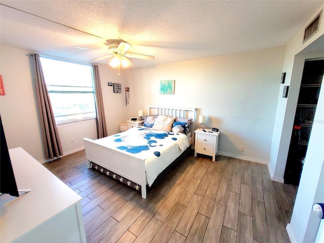 bedroom with ceiling fan, dark hardwood / wood-style floors, and a textured ceiling