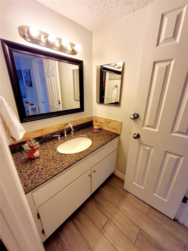 bathroom with hardwood / wood-style floors, vanity, and a textured ceiling