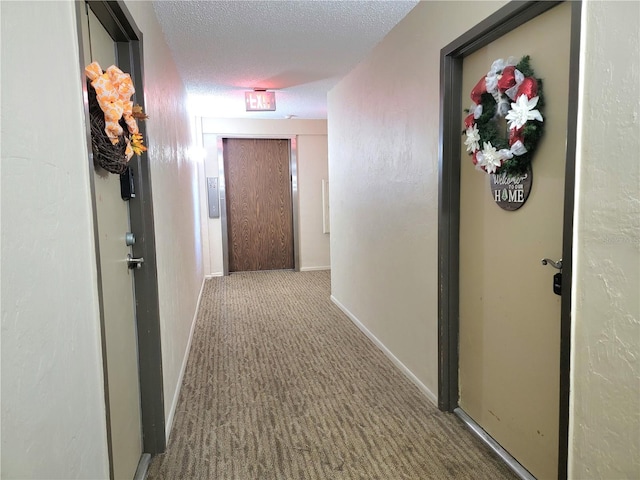 hall featuring dark carpet and a textured ceiling