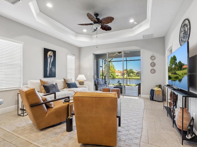 tiled living room featuring a tray ceiling, ceiling fan, and crown molding