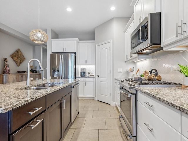 kitchen with white cabinetry, sink, stainless steel appliances, pendant lighting, and light tile patterned floors