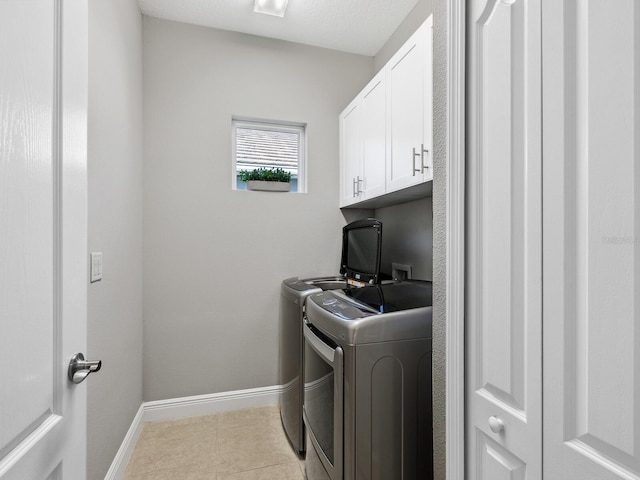 laundry room with light tile patterned flooring, cabinets, separate washer and dryer, and a textured ceiling