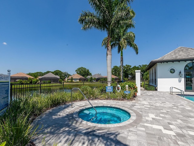 view of swimming pool featuring a community hot tub, a water view, and a patio