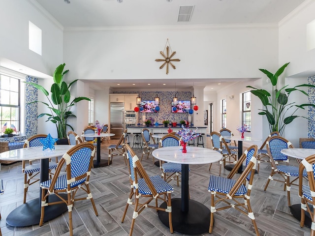 dining area with parquet floors, crown molding, and a high ceiling