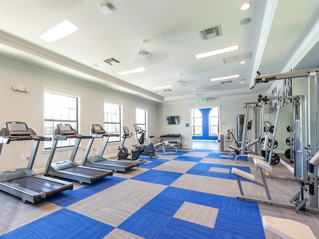 gym with ceiling fan, a healthy amount of sunlight, a textured ceiling, and ornamental molding