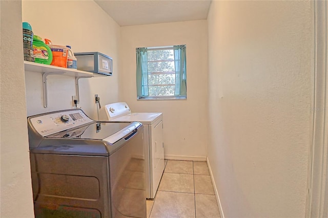 laundry area featuring washing machine and clothes dryer and light tile patterned floors