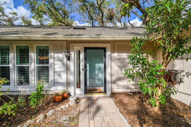 doorway to property with roof with shingles