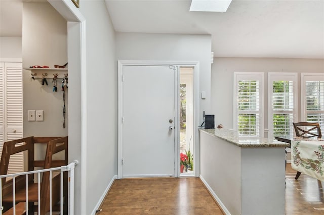 foyer featuring wood-type flooring and a skylight