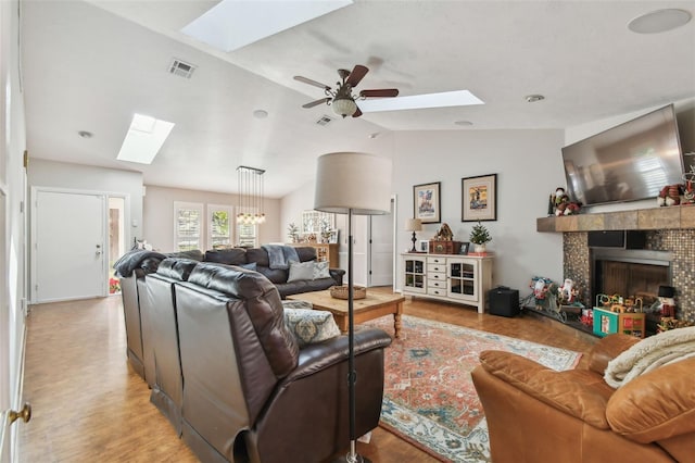 living room featuring ceiling fan, a fireplace, vaulted ceiling, and light hardwood / wood-style flooring