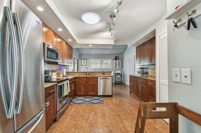 kitchen with pendant lighting, sink, light stone countertops, and stainless steel appliances