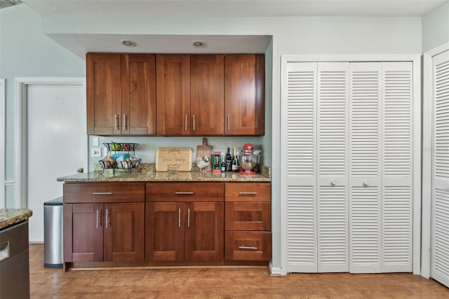 bar featuring light stone countertops and light hardwood / wood-style flooring