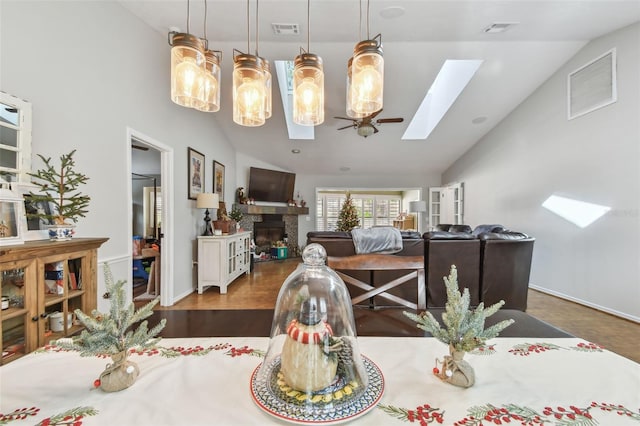 dining space with vaulted ceiling with skylight and dark wood-type flooring