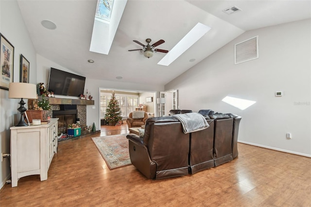 living room with a tiled fireplace, ceiling fan, light hardwood / wood-style floors, and lofted ceiling