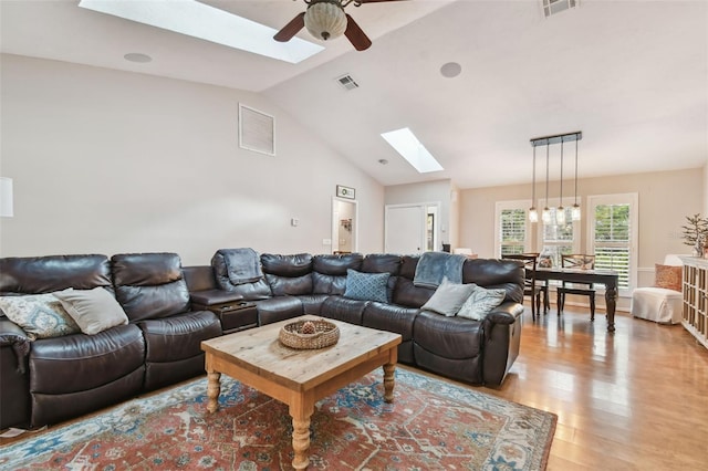 living room featuring light hardwood / wood-style floors, ceiling fan, and vaulted ceiling with skylight