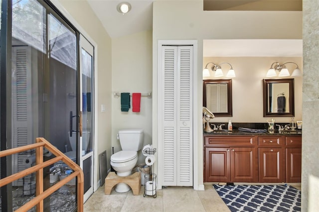 bathroom featuring toilet, vanity, vaulted ceiling, and tile patterned floors