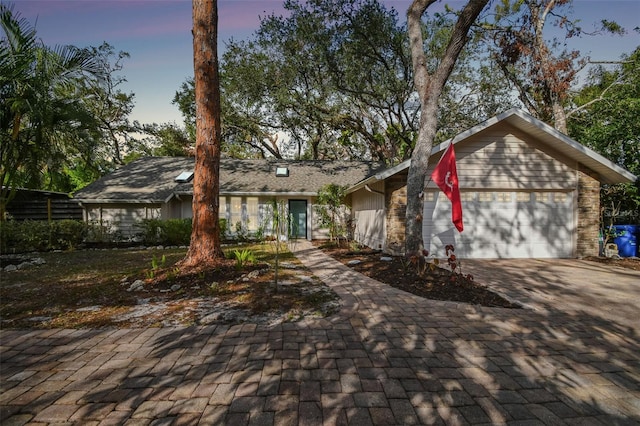 view of front of home with an attached garage, decorative driveway, and fence