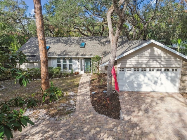 view of front of home featuring a garage, decorative driveway, and a shingled roof