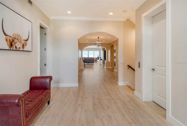 hallway with crown molding, light hardwood / wood-style floors, and a notable chandelier