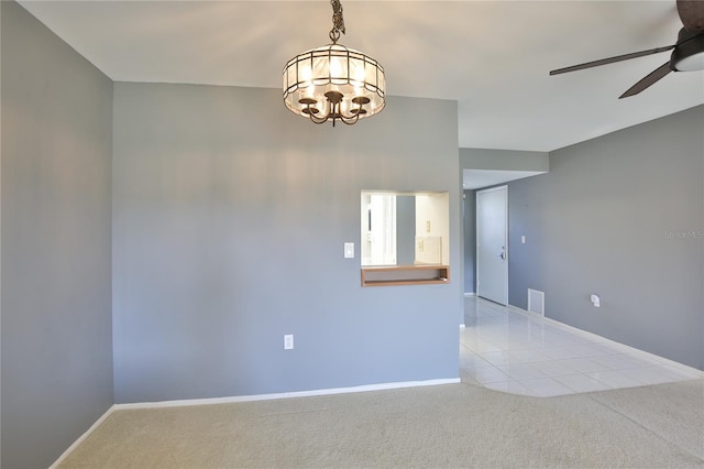 carpeted spare room featuring ceiling fan with notable chandelier