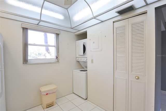 clothes washing area featuring light tile patterned floors and stacked washer and dryer