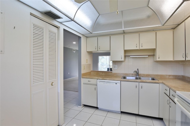 kitchen with white appliances, sink, light tile patterned floors, and cream cabinets