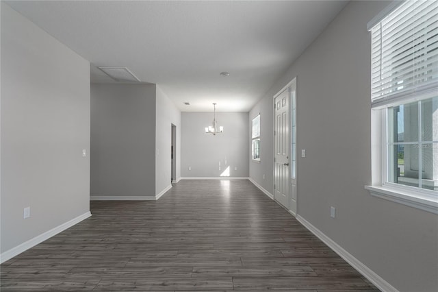 unfurnished room with plenty of natural light, dark hardwood / wood-style flooring, and a chandelier