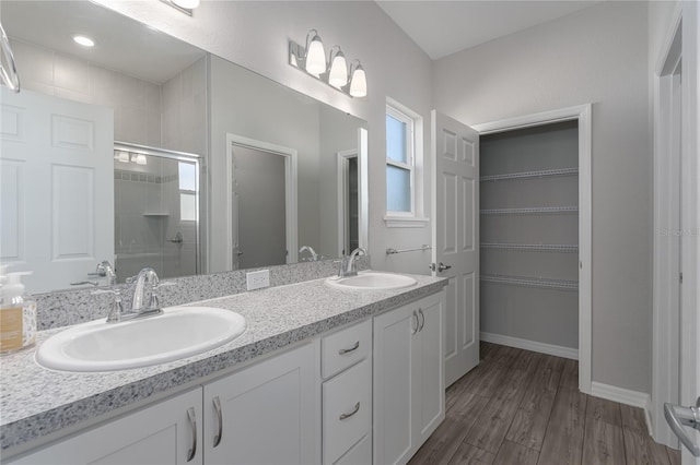 bathroom with hardwood / wood-style floors, vanity, and a shower with door