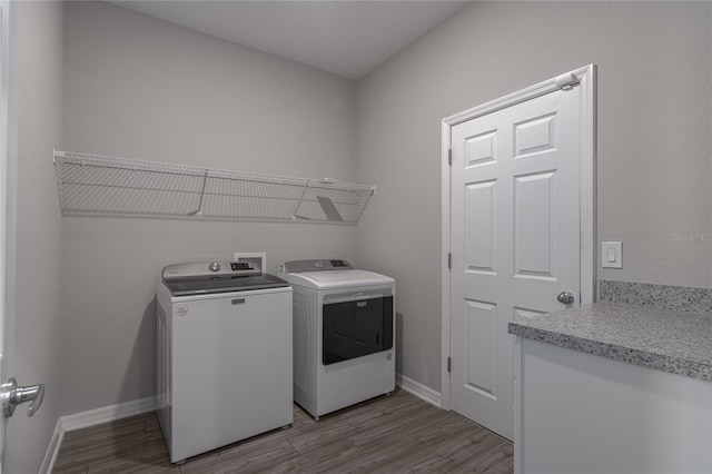 clothes washing area featuring washer and clothes dryer and light hardwood / wood-style flooring