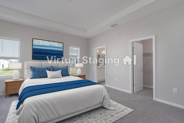 bedroom with a walk in closet, carpet floors, a tray ceiling, connected bathroom, and a closet