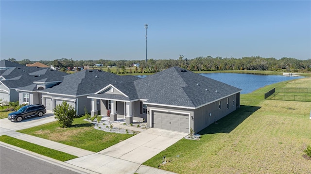 view of front of house featuring a water view, covered porch, a front yard, and a garage