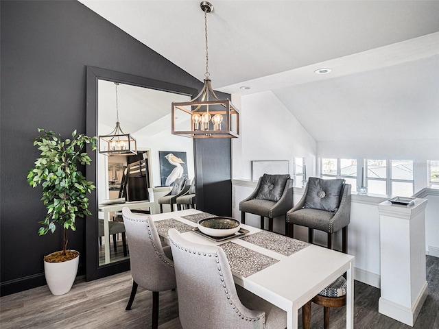 dining space featuring wood-type flooring, lofted ceiling, and an inviting chandelier