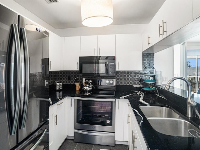 kitchen with sink, stainless steel appliances, dark tile patterned floors, backsplash, and white cabinets