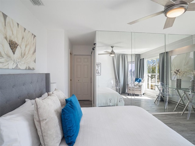 bedroom featuring ceiling fan, a barn door, and dark hardwood / wood-style floors