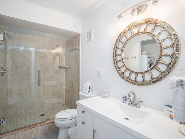 bathroom with washer / clothes dryer, vanity, a shower with shower door, and toilet