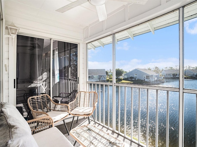 sunroom / solarium featuring ceiling fan and a water view