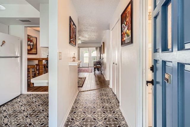 corridor with hardwood / wood-style floors and a textured ceiling