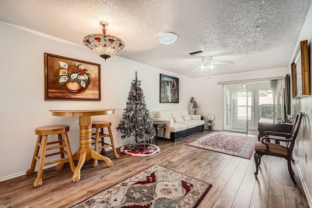 living room with wood-type flooring, a textured ceiling, and ceiling fan