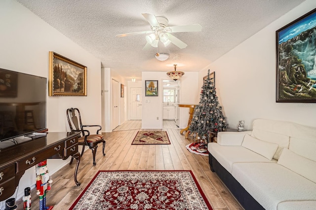 living room featuring ceiling fan, sink, a textured ceiling, and light wood-type flooring