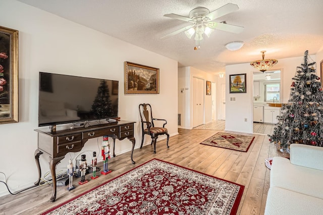 living room featuring ceiling fan, light hardwood / wood-style flooring, a textured ceiling, and sink