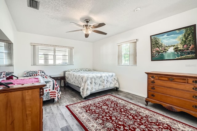 bedroom featuring hardwood / wood-style flooring, ceiling fan, and a textured ceiling