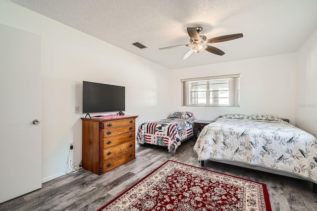 bedroom with ceiling fan, wood-type flooring, and a textured ceiling