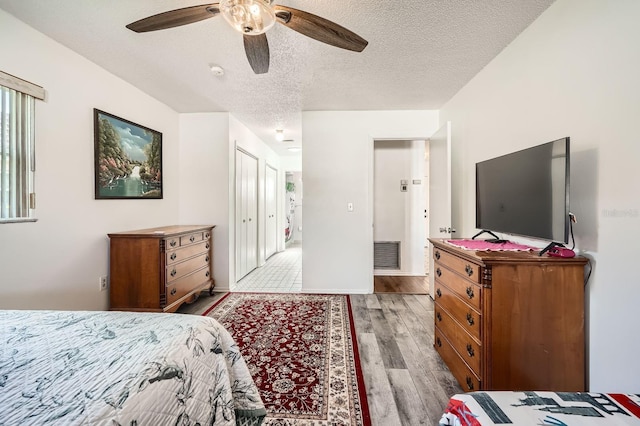 bedroom featuring ceiling fan, light wood-type flooring, and a textured ceiling