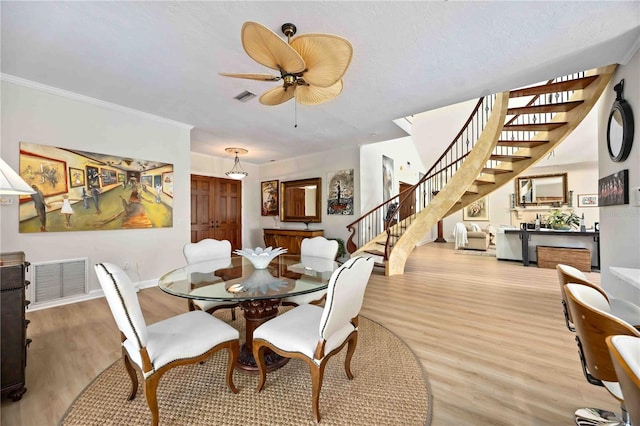 dining space featuring a textured ceiling, ceiling fan, crown molding, and light hardwood / wood-style flooring