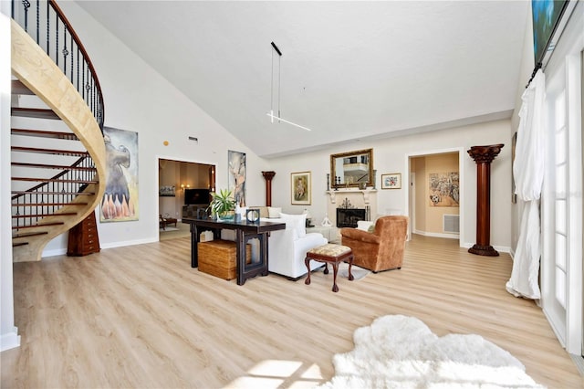 living room featuring a towering ceiling, a healthy amount of sunlight, and light wood-type flooring