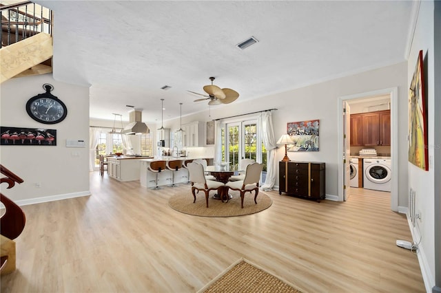 dining space featuring sink, light hardwood / wood-style flooring, washer and dryer, ceiling fan, and a textured ceiling